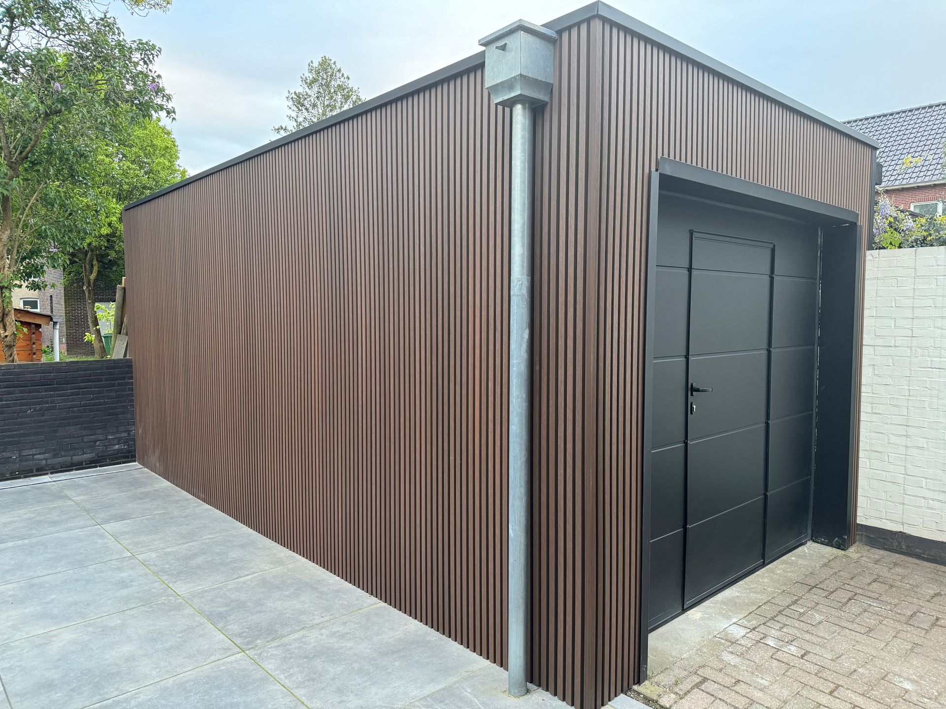 Een garage met een houten gevelbeplating en een zwarte deur.