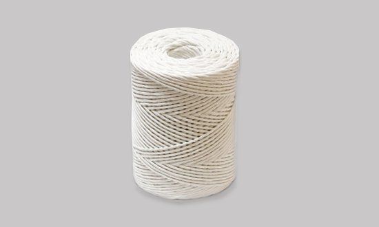 Un rollo de cuerda blanca reposa sobre una superficie gris.