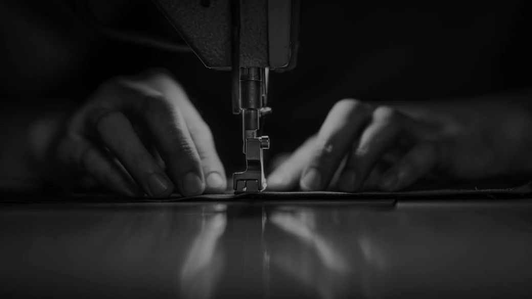 Macchina da cucire professionale affiancata da una ricamatrice in un laboratorio tecnico ordinato.