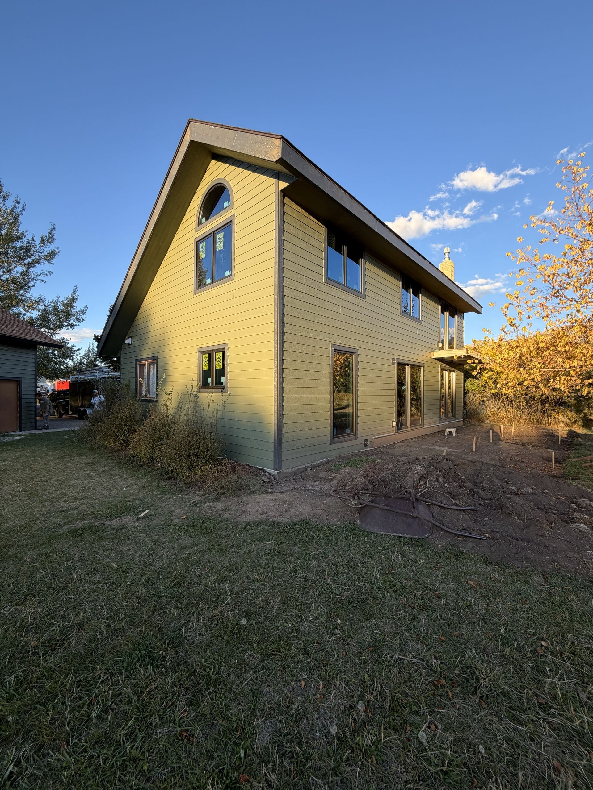 A man is standing on a ladder in front of a house.