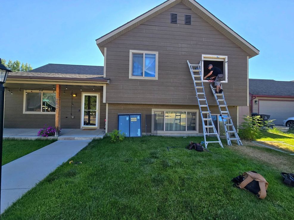 A man is standing on a ladder in front of a house.