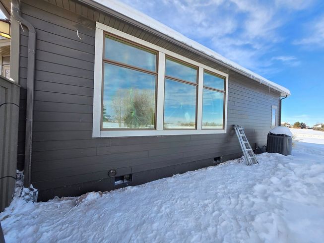 A house with a lot of windows is covered in snow.