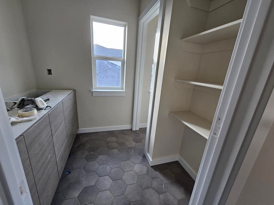 A closet with a window and shelves in a house under construction.