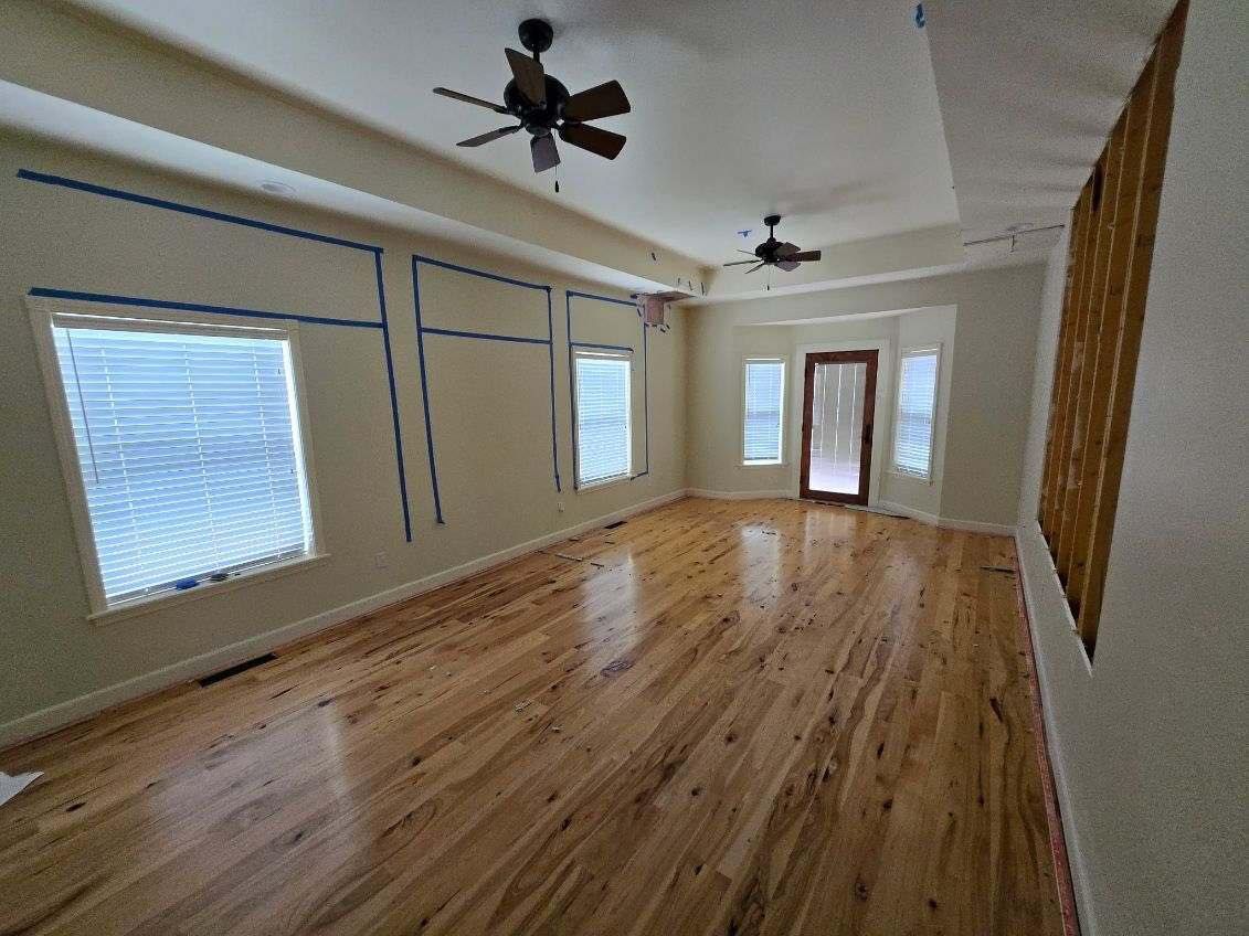 An empty living room with hardwood floors and a ceiling fan.