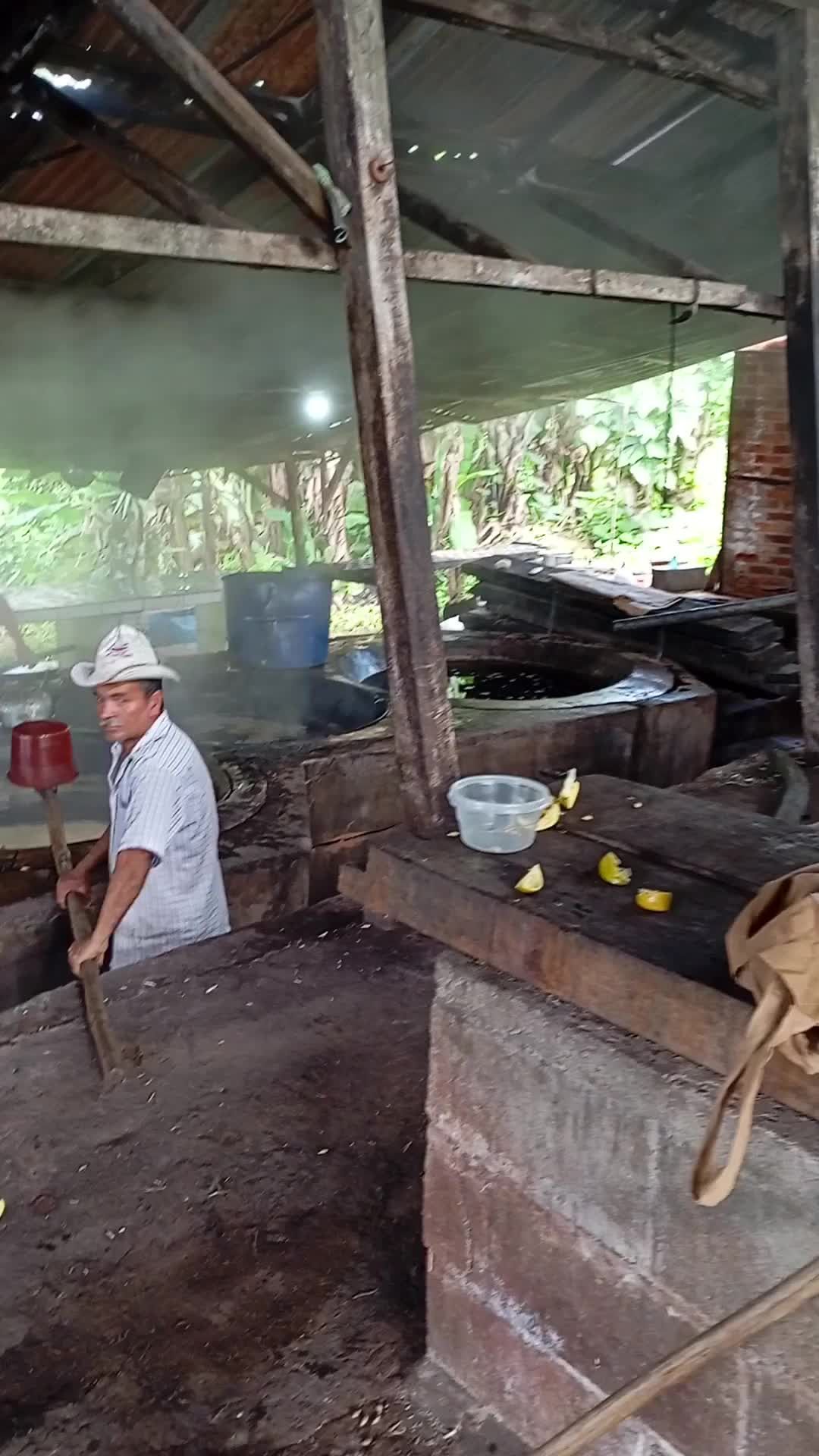 A man in a hat is sitting on a wooden table in a kitchen.