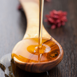 Honey is being poured into a wooden spoon