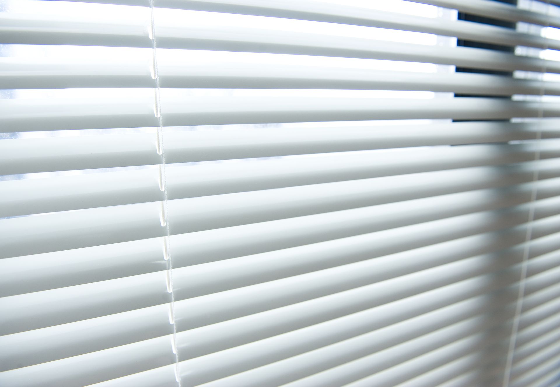 White window blinds, angled open, letting light in.