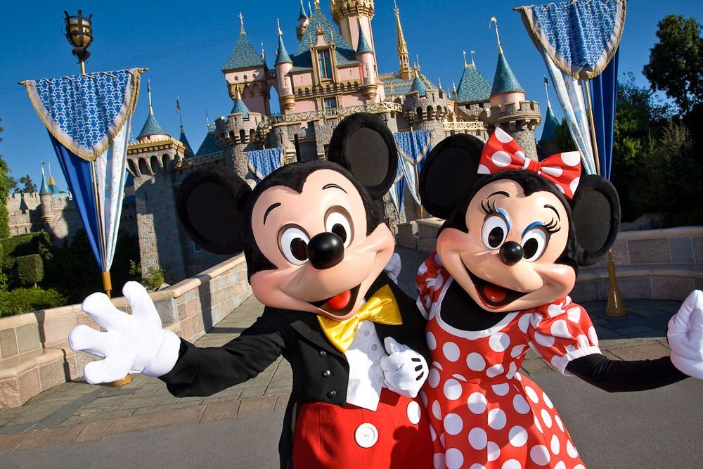 Mickey mouse and minnie mouse pose in front of a castle