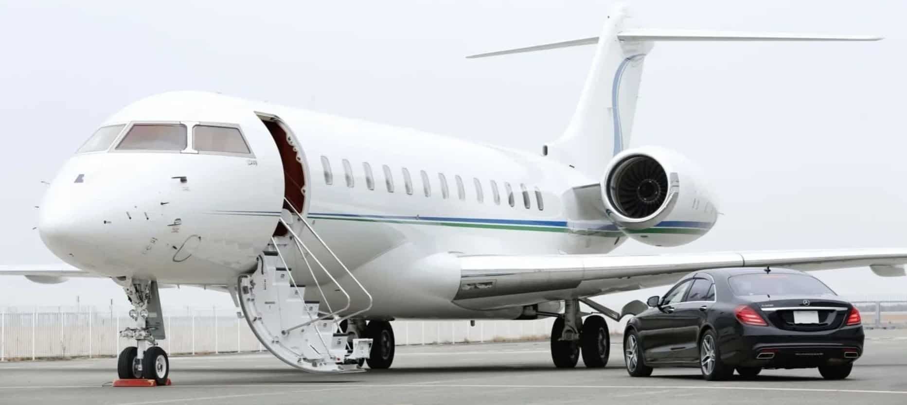 A private jet is parked next to a black car