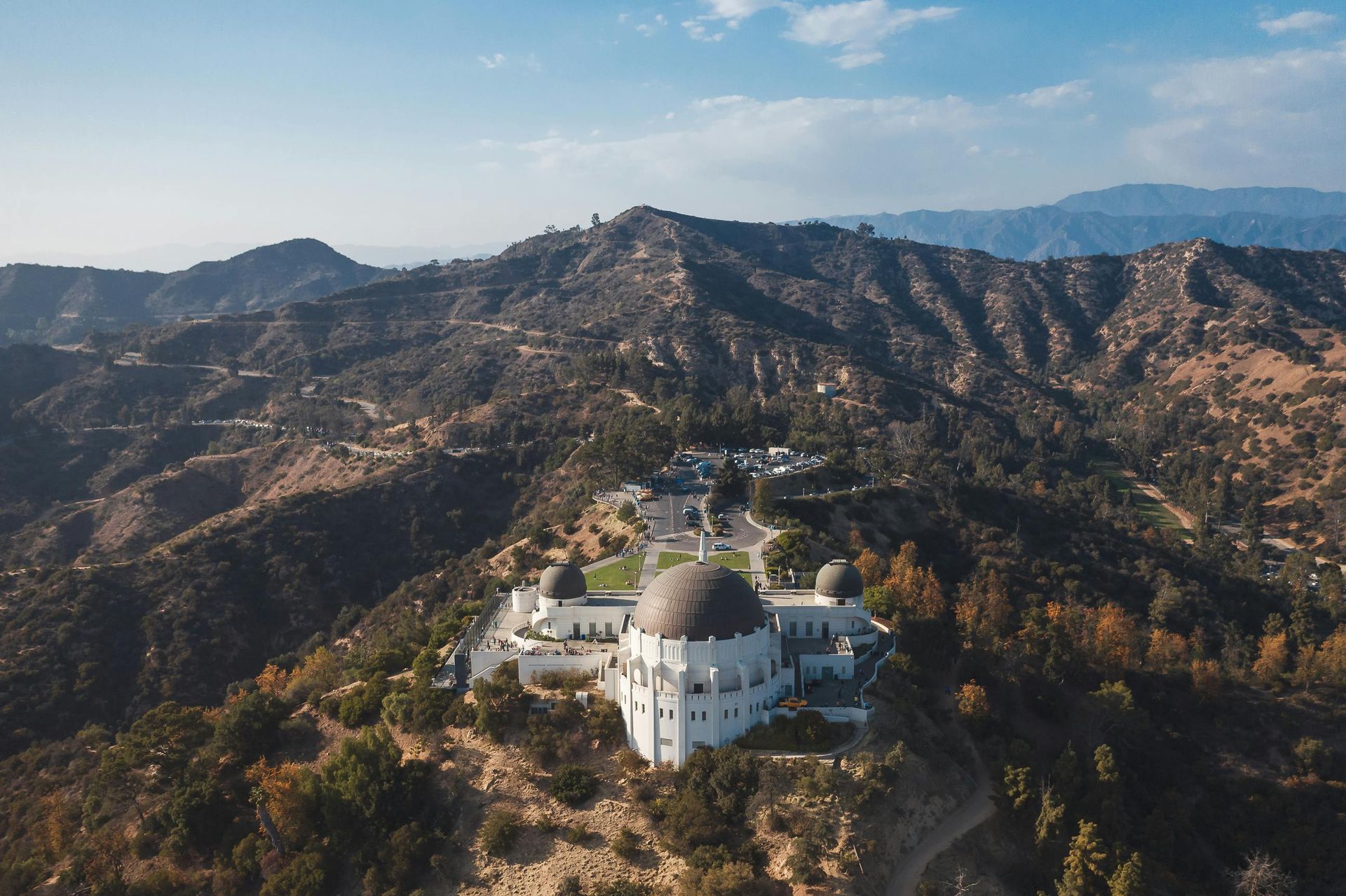 An aerial view of the griffith observatory on top of a hill surrounded by mountains.