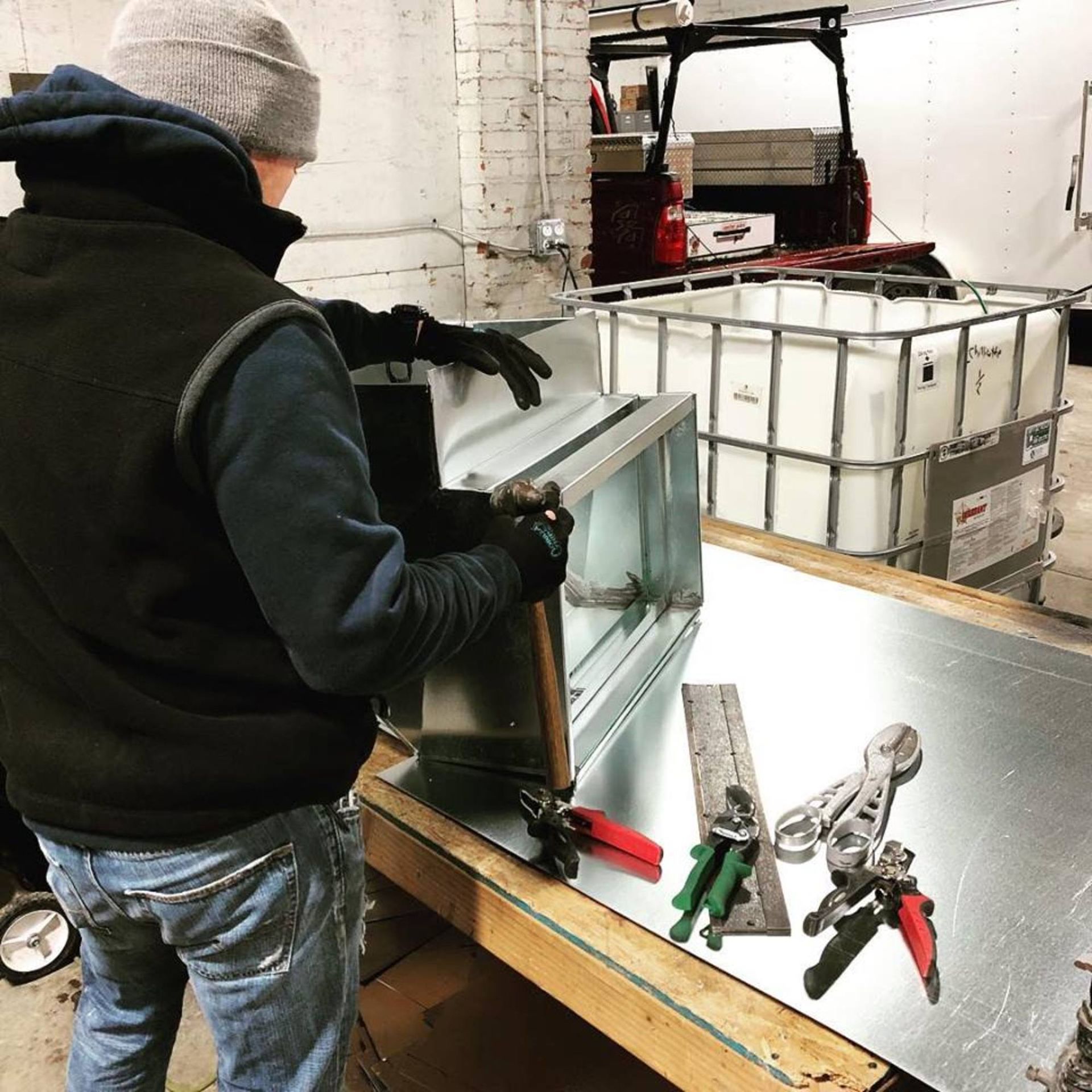 A man in a black vest is working on a piece of metal