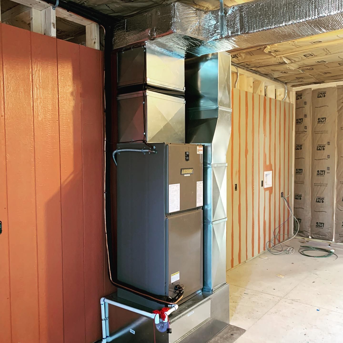 An air conditioner is sitting in a room with wooden walls.