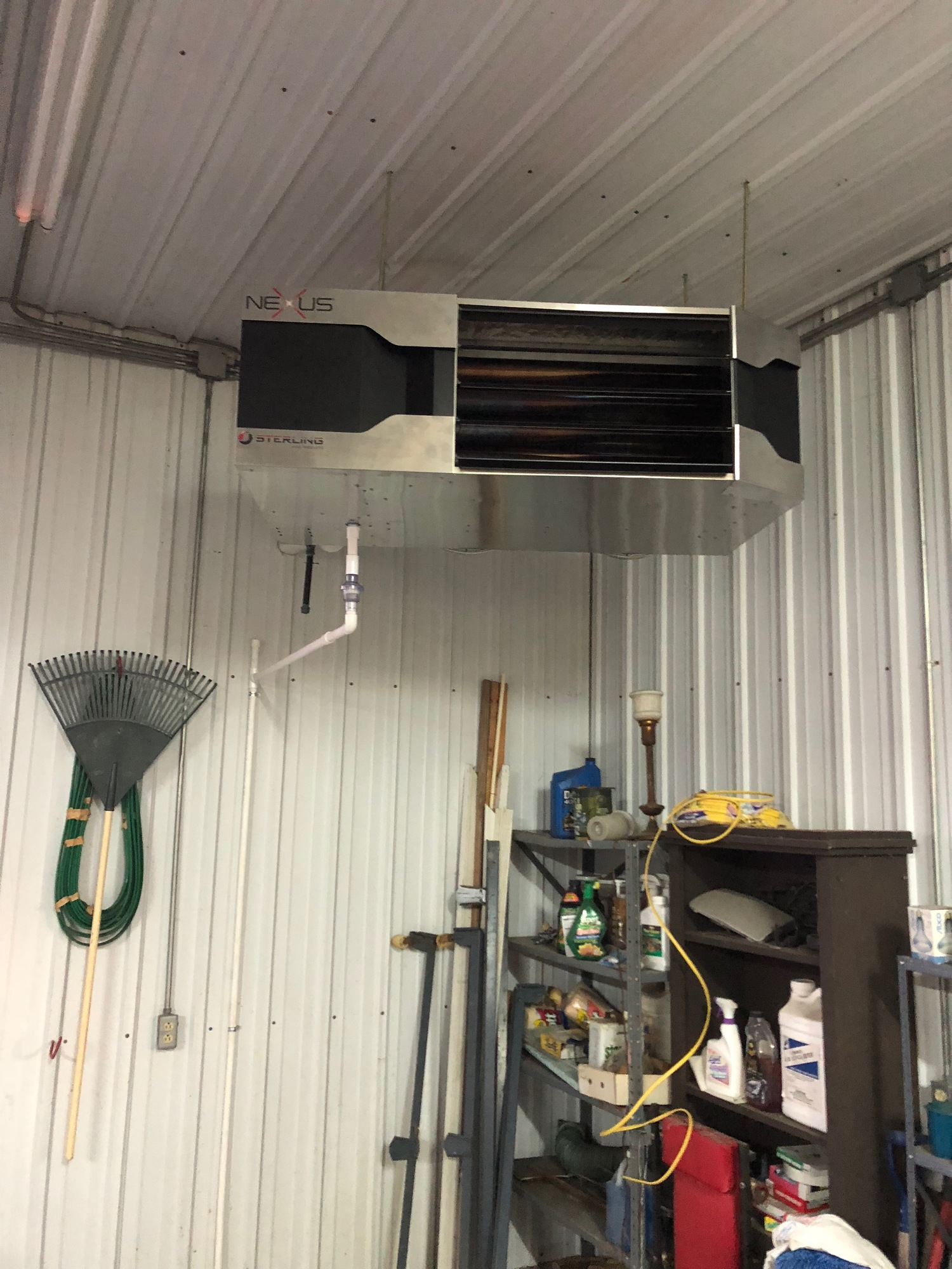 A large heater is hanging from the ceiling of a garage.