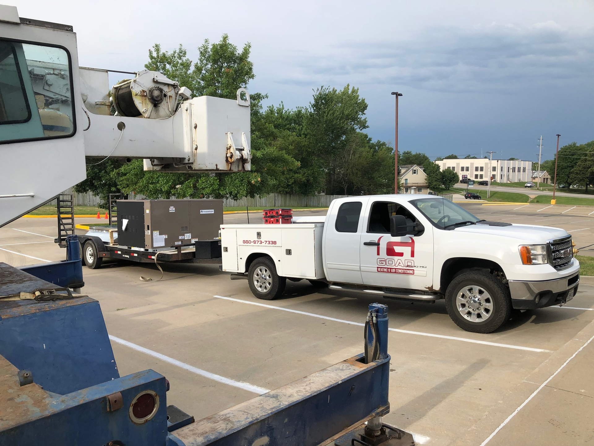 A white truck with a trailer attached to it is parked in a parking lot.