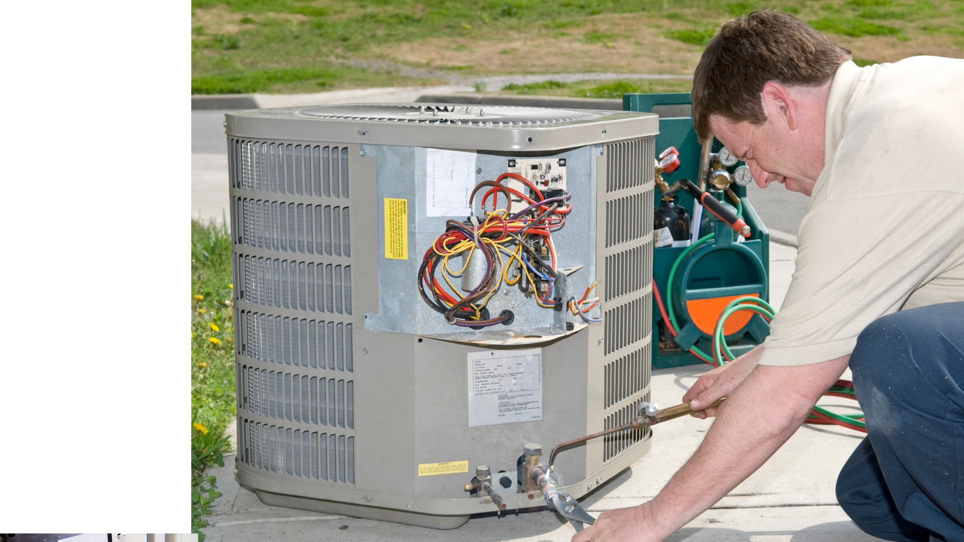 A man is working on an air conditioner outside of a building.