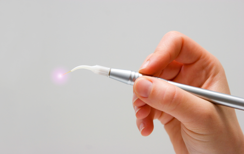 A person is holding a pen with a light coming out of it.