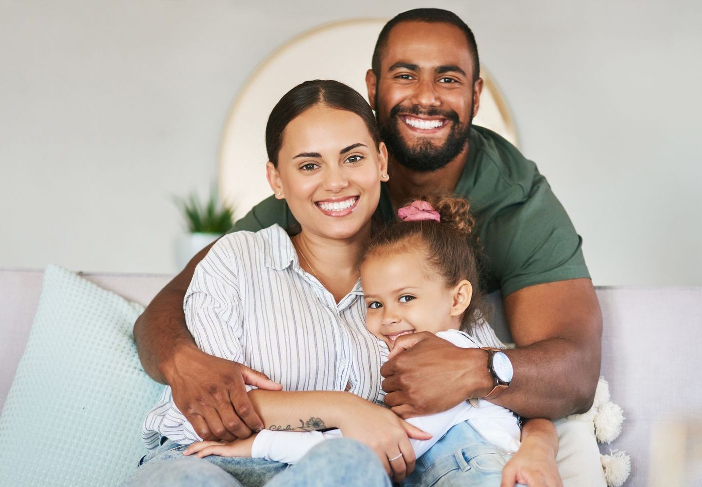 Smiling family of three on a couch, embracing each other.