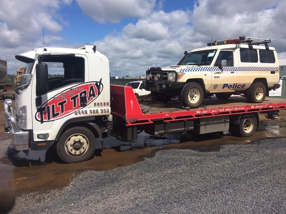 A Police Suv on a Red Flatbed Tow Truck Labeled Tilt Tray Under a Cloudy Blue Sky