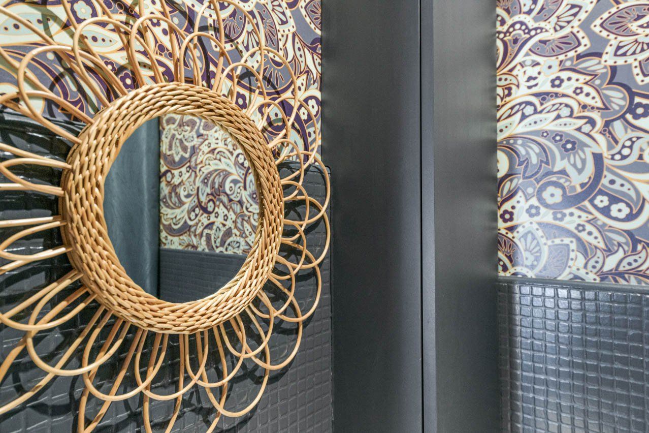 Miroir en rotin sur papier peint graphique dans un appartement