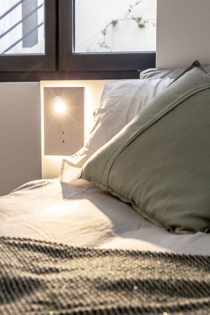 Lampe à côté du lit dans une chambre après travaux de rénovation