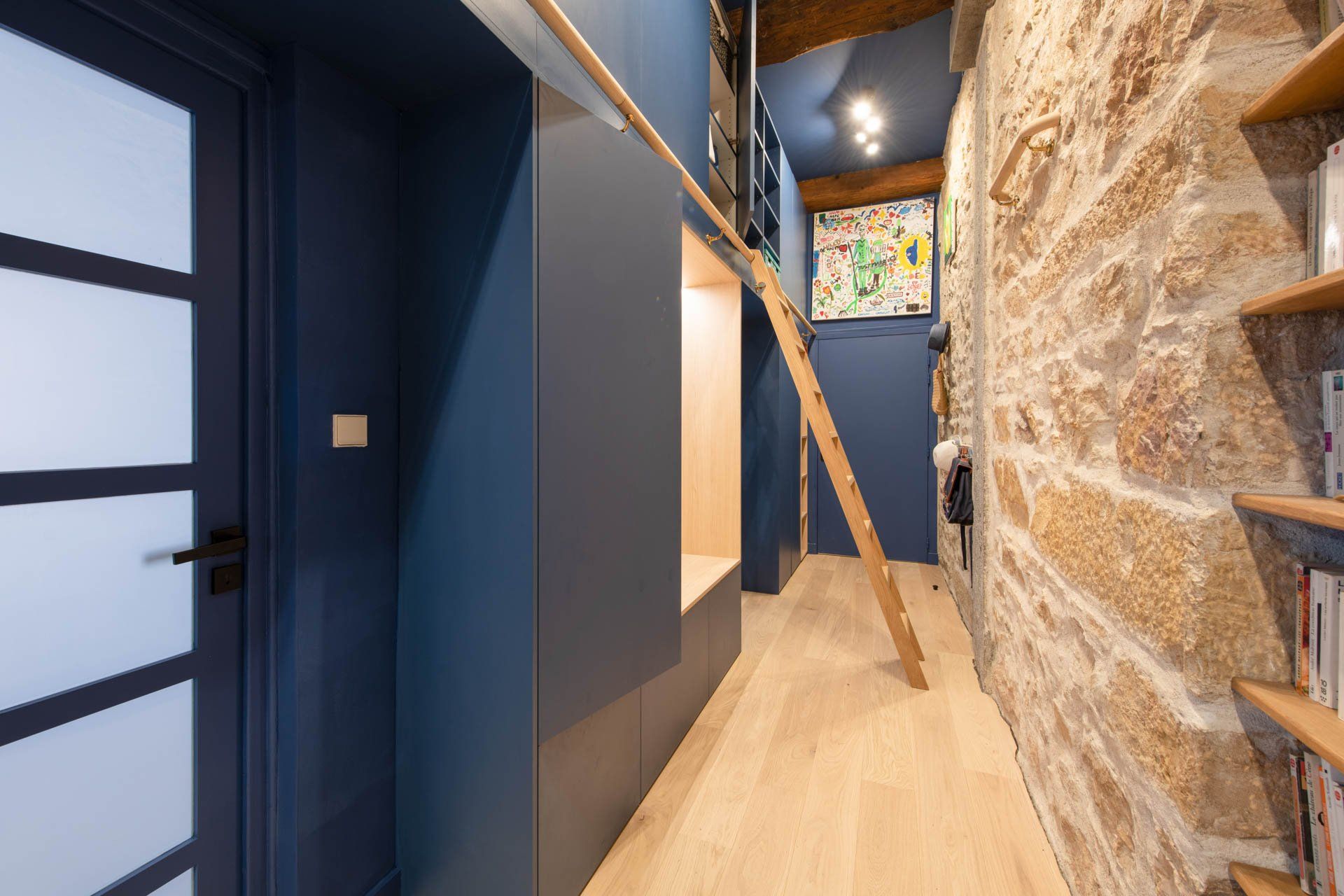 Le couloir de l'appartement rénové avec la bibliothèque sur mesure