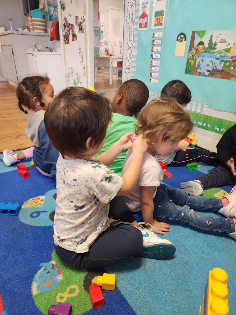 A group of children are sitting on the floor playing with toys.