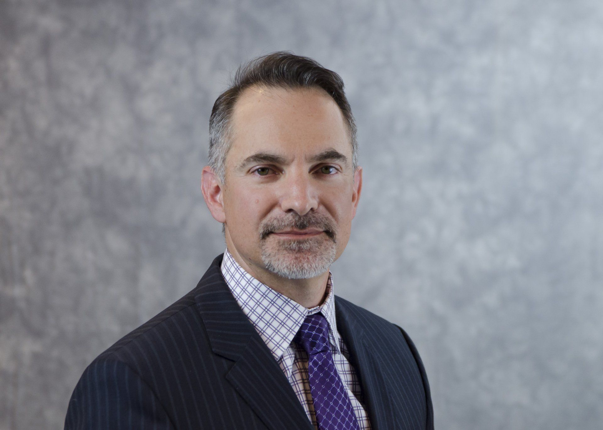 A man in a suit and tie is smiling for the camera.