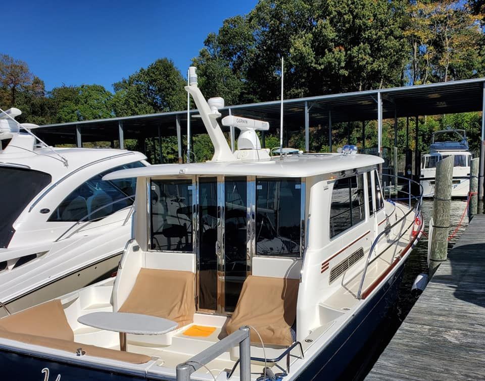White cabin cruiser docked at a marina with brown cushions, a radar, and a clear blue sky.