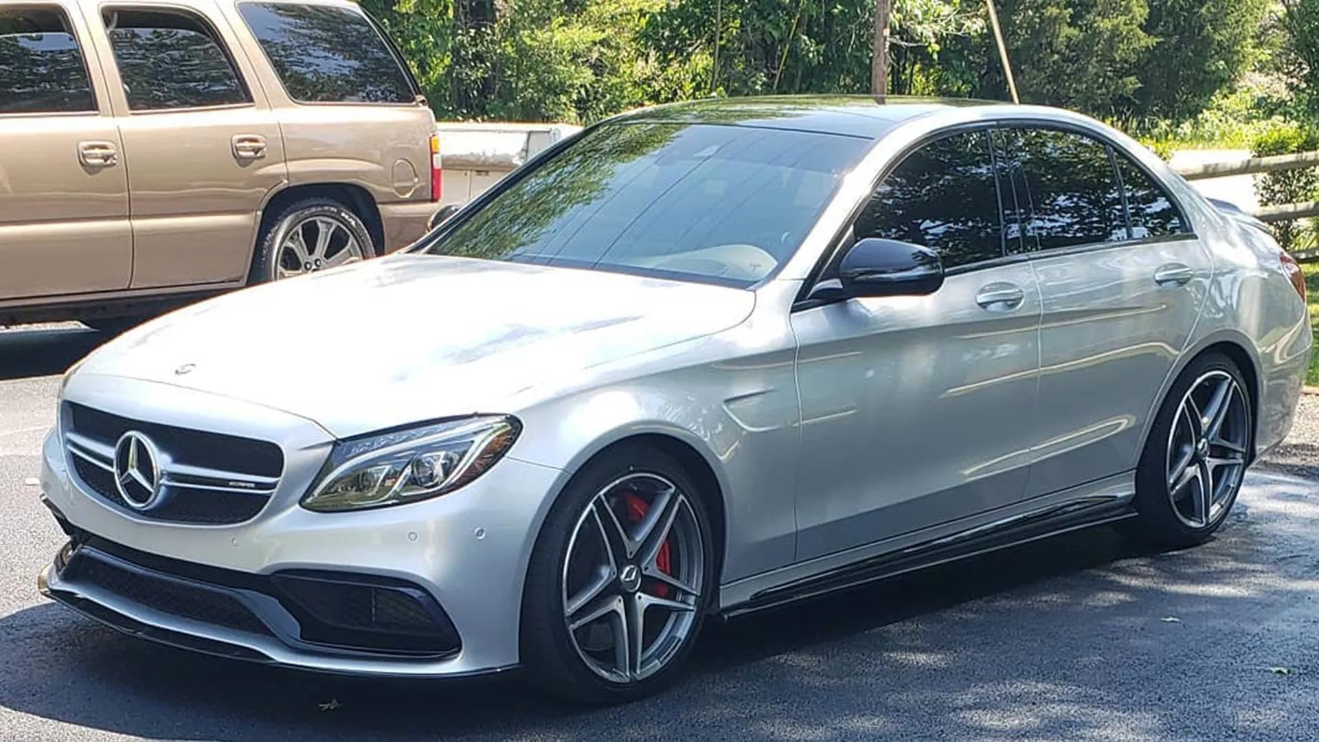 Silver Mercedes-AMG C63 sedan parked outdoors with tinted windows and black accents, red brake calipers.