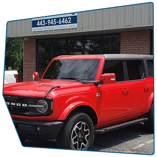 Red Ford Bronco parked in front of a brick building with a business sign above the door. Red Ford Bronco parked in front of a brick building with a business sign above the door.
