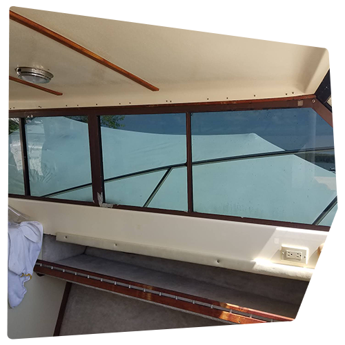 Interior of a boat cabin with windows, wood trim, and a cream-colored ceiling and walls. Interior of a boat cabin with windows, wood trim, and a cream-colored ceiling and walls.