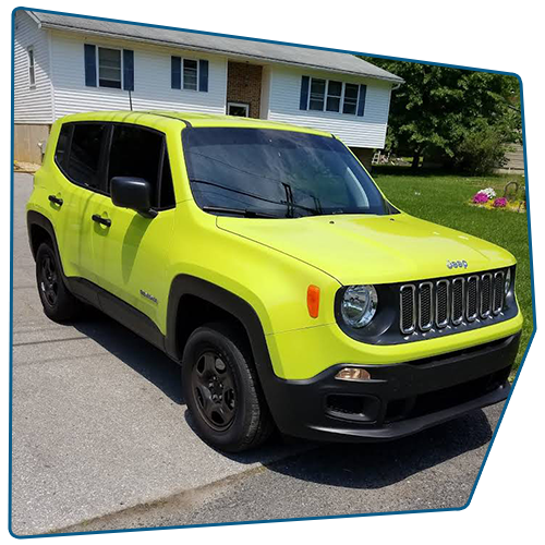 Bright yellow Jeep Renegade parked on a paved driveway in front of a white house with blue shutters. Bright yellow Jeep Renegade parked on a paved driveway in front of a white house with blue shutters.