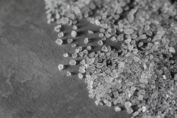 Small translucent salt crystals on grey table.