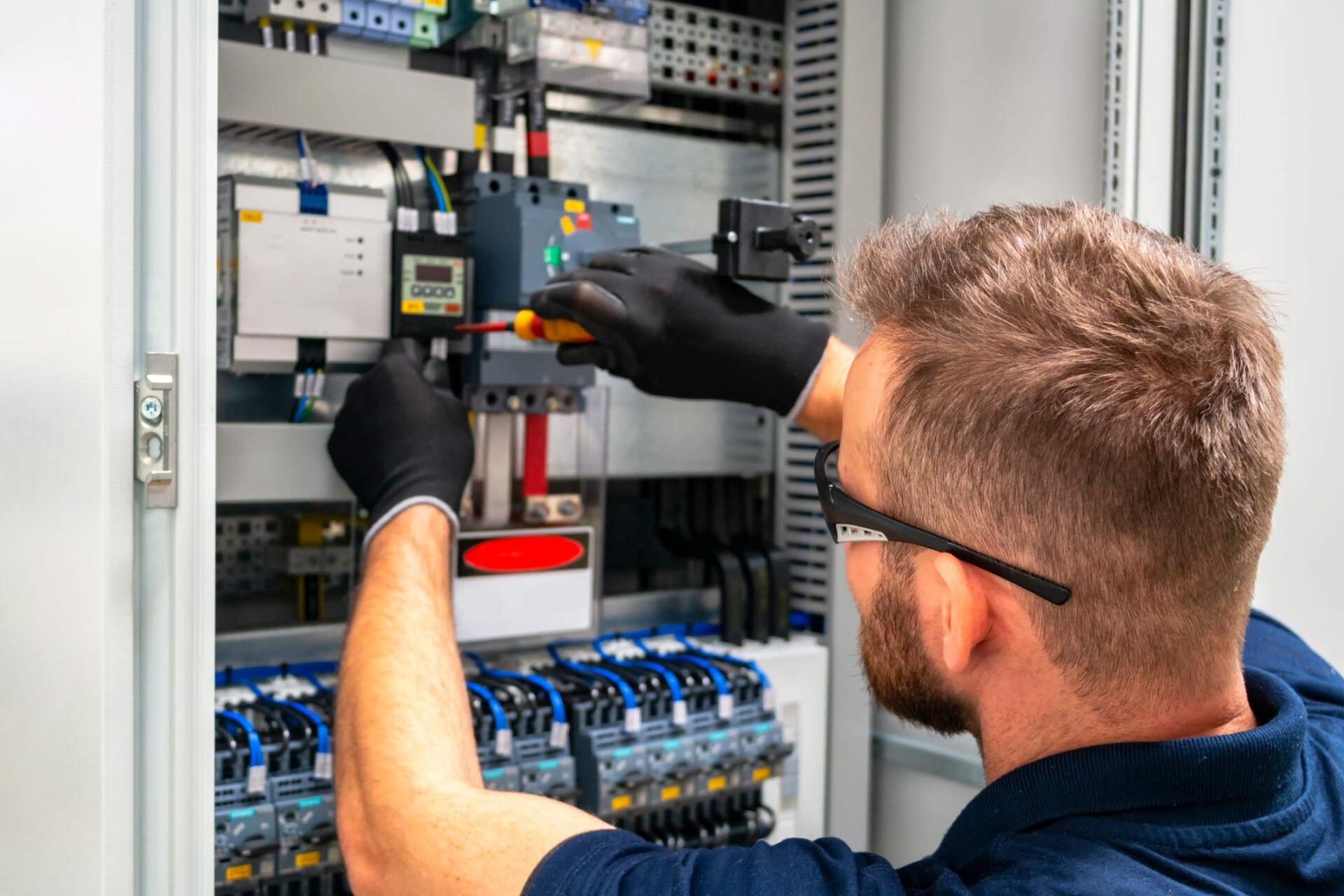 Electrician working at distribution board | Wingham, NSW | KMF Electrical & Solar