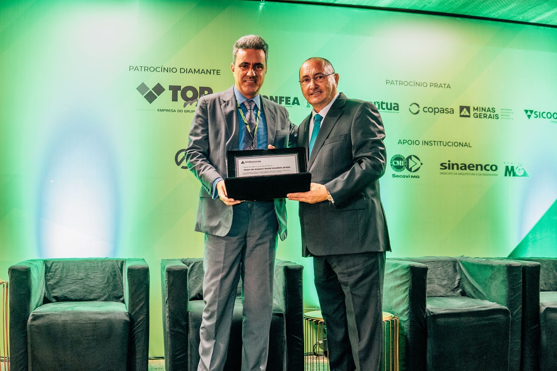 Two men in suits are standing next to each other holding a plaque.