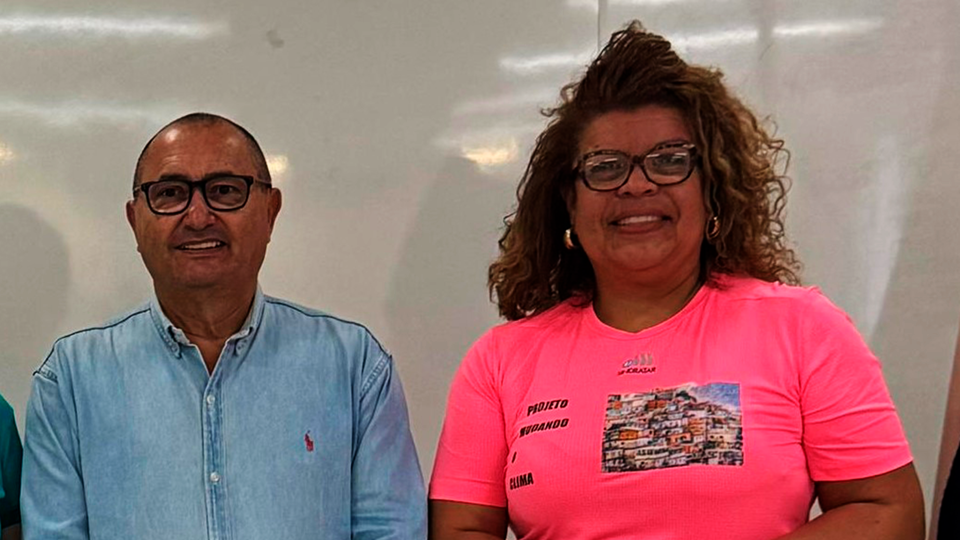 Um homem e uma mulher estão de pé, um ao lado do outro, em frente a um quadro branco.