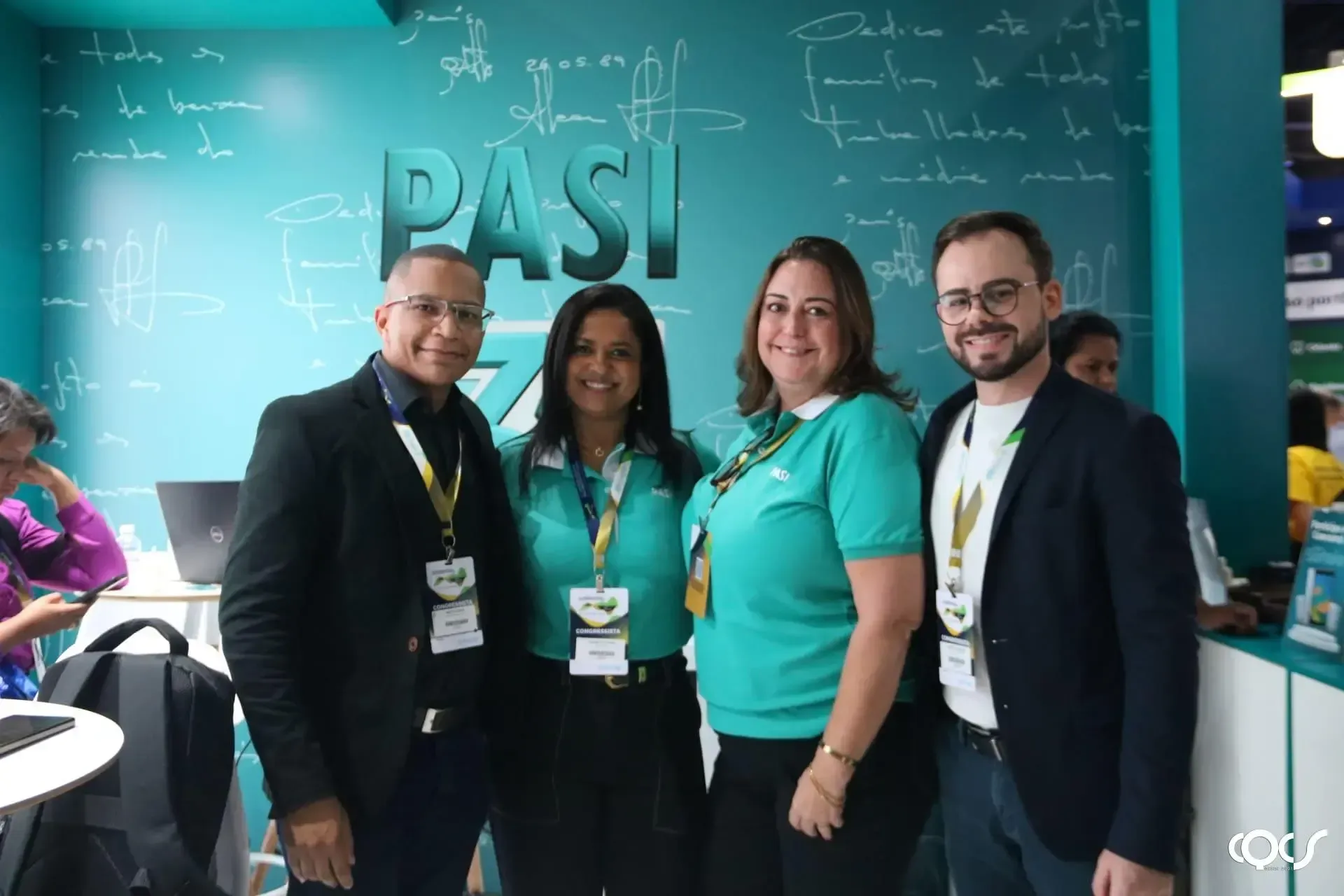 Um grupo de pessoas está posando para uma foto em frente a uma parede azul.