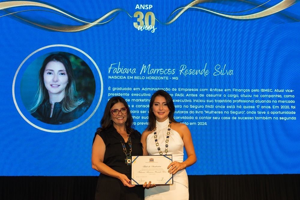 Duas mulheres estão de pé, uma ao lado da outra, segurando um certificado.