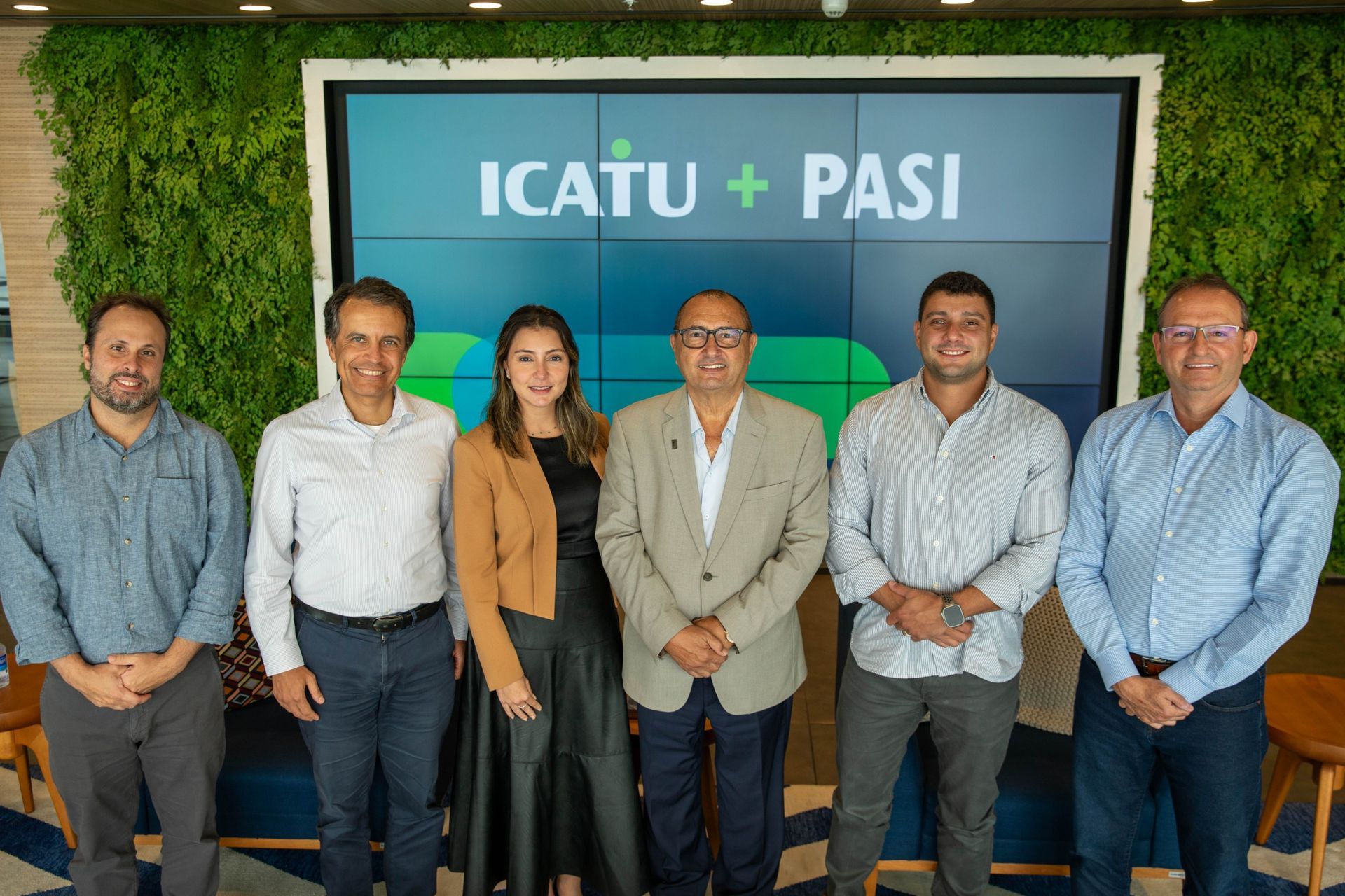 Um grupo de pessoas está posando para uma foto em frente a uma tela grande.
