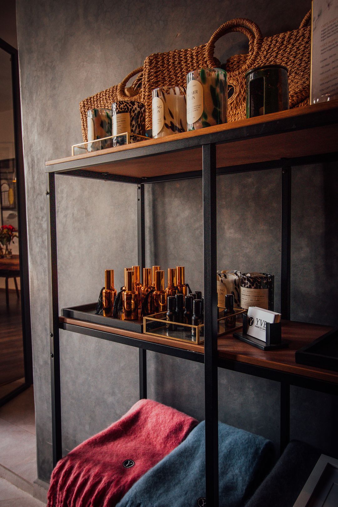 A shelf filled with bottles , baskets , and blankets.