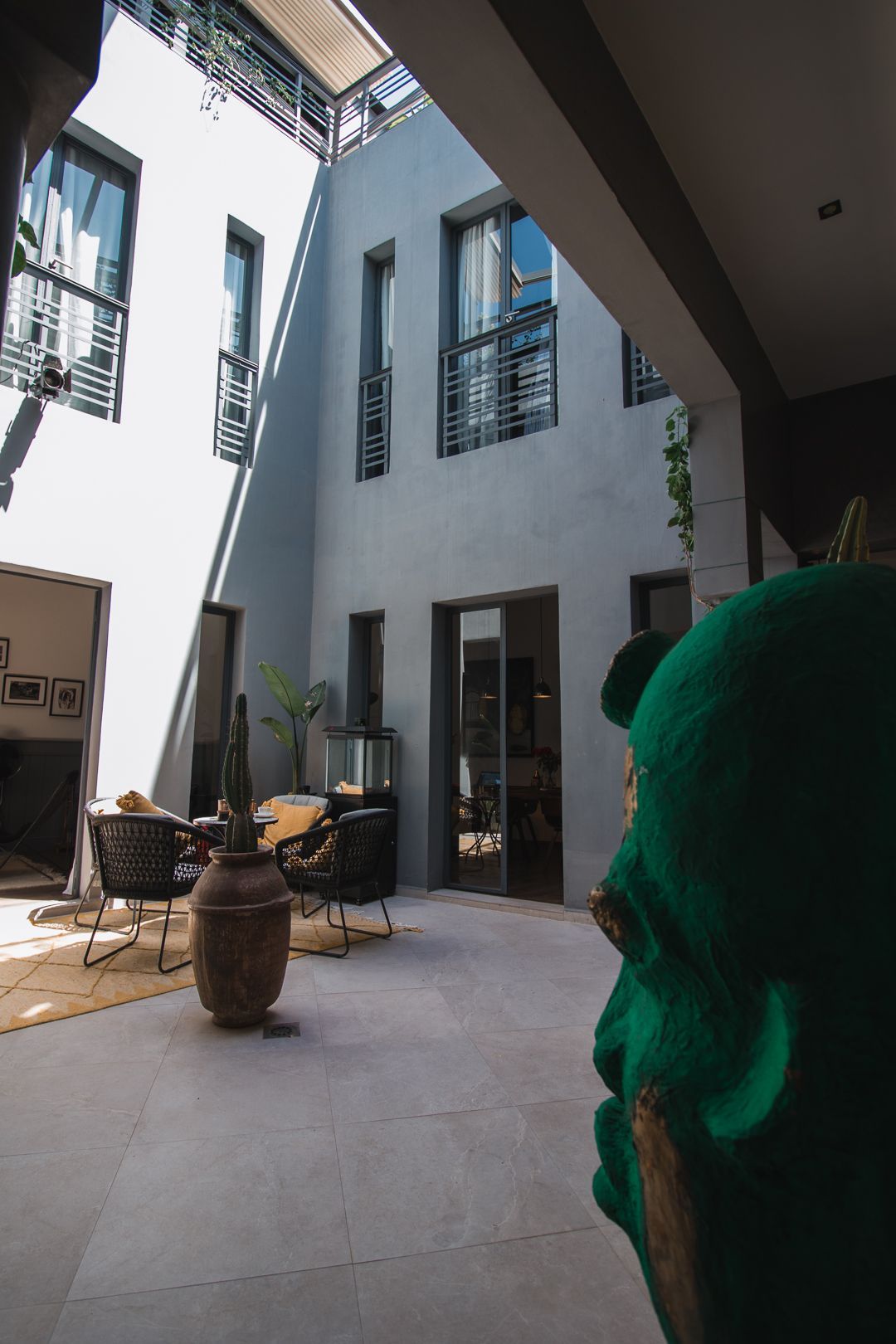 A green statue is standing in the middle of a courtyard in front of a building.