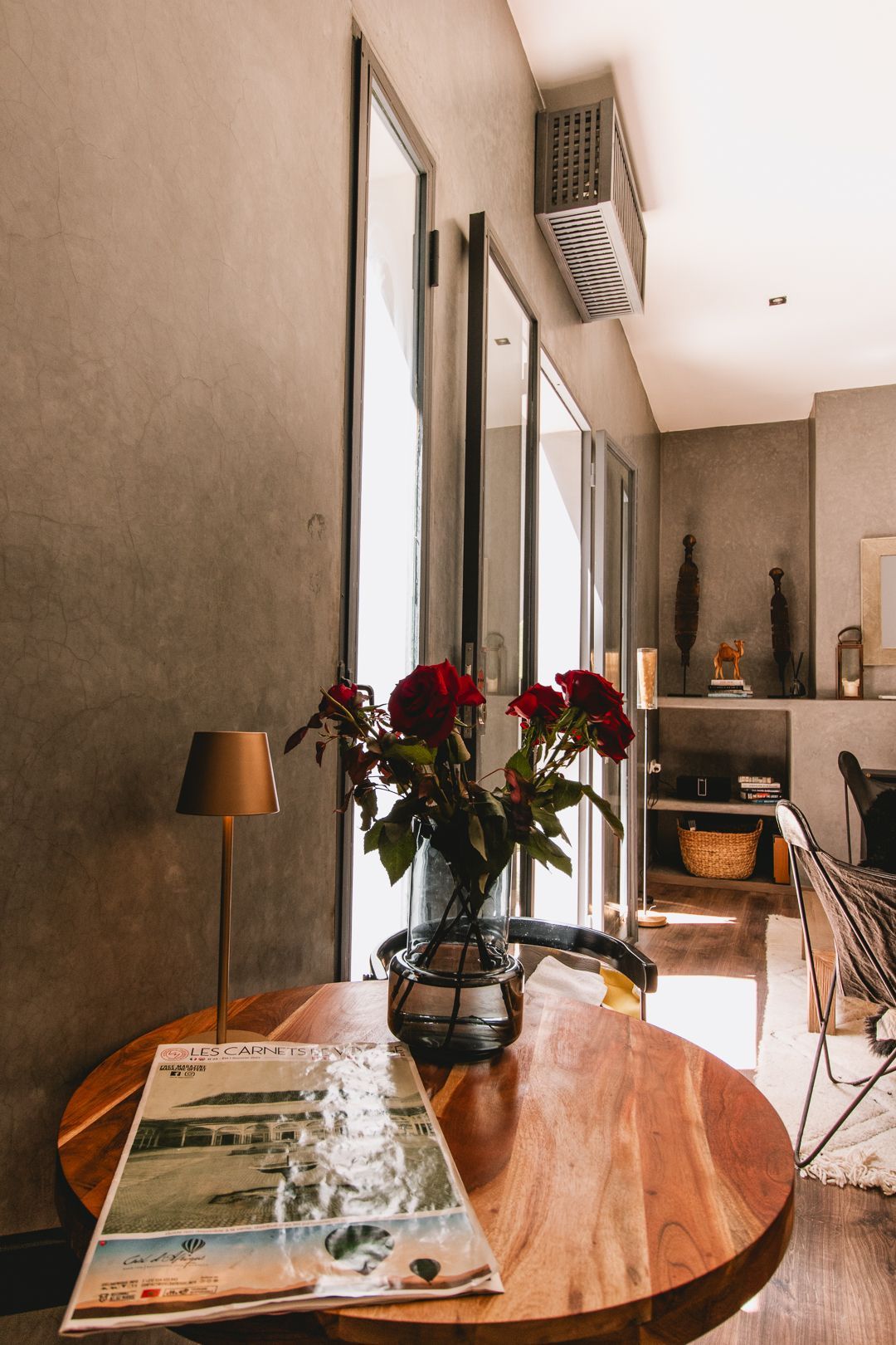 A wooden table with a vase of flowers and a magazine on it.