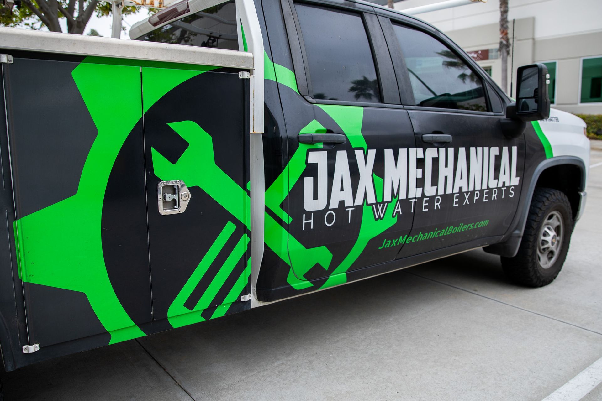 Black and green Jax Mechanical service truck with company logo and text parked on a concrete surface.