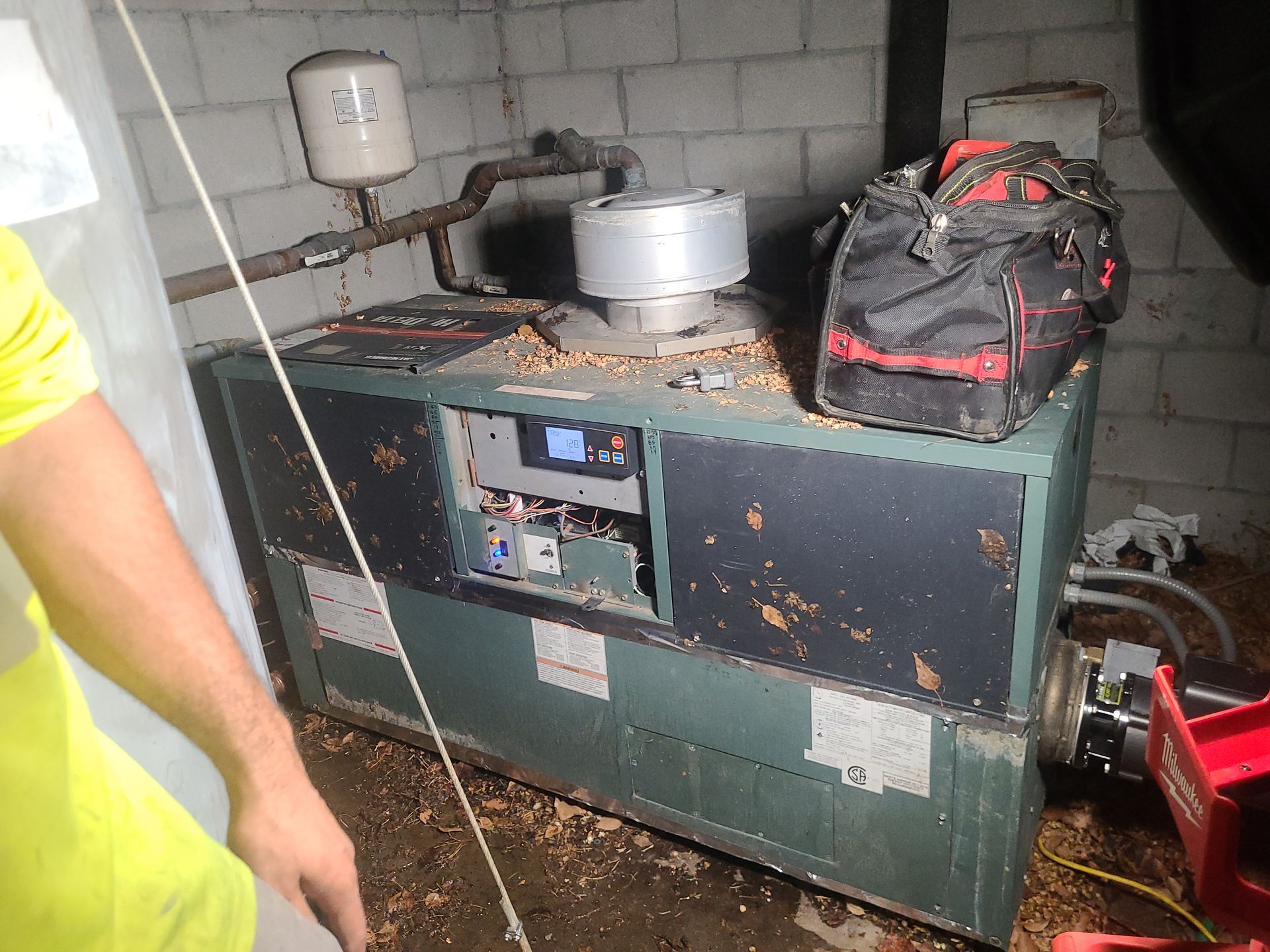 A wood pellet boiler in a basement with a toolbox on top.