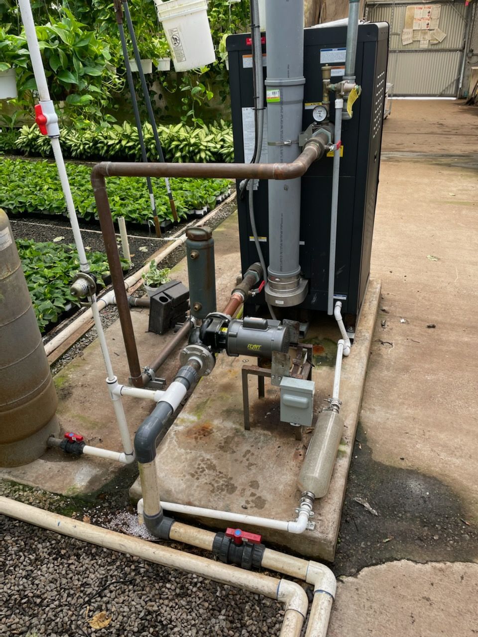 A greenhouse water heating system with pipes, valves, and a pump.