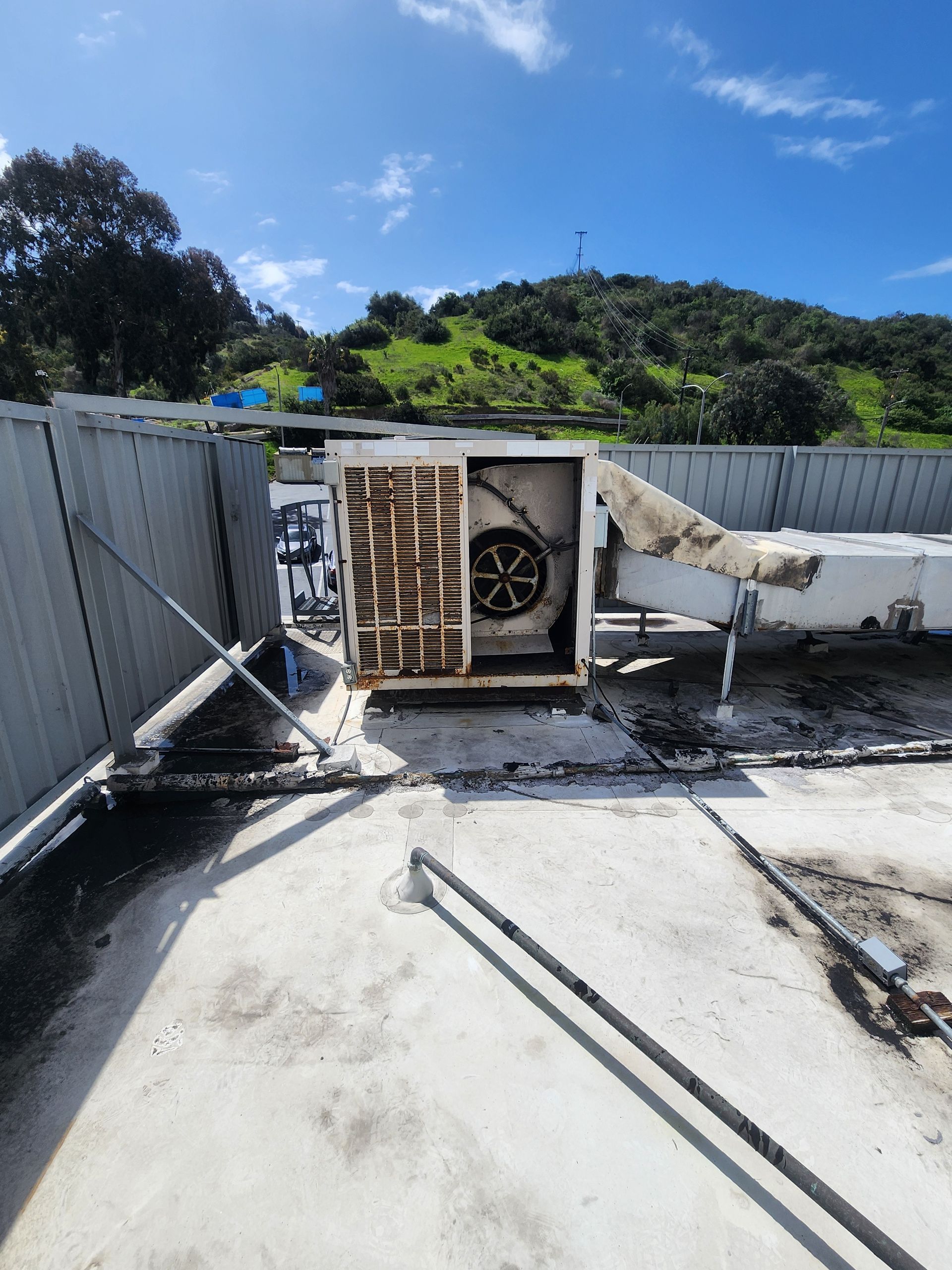 HVAC unit on a rooftop, with a fan visible. Blackened areas suggest fire damage.