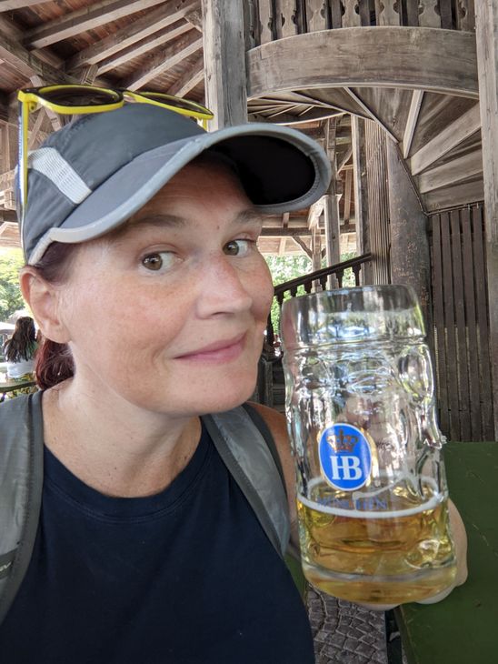 A woman in a hat is holding a glass of beer.