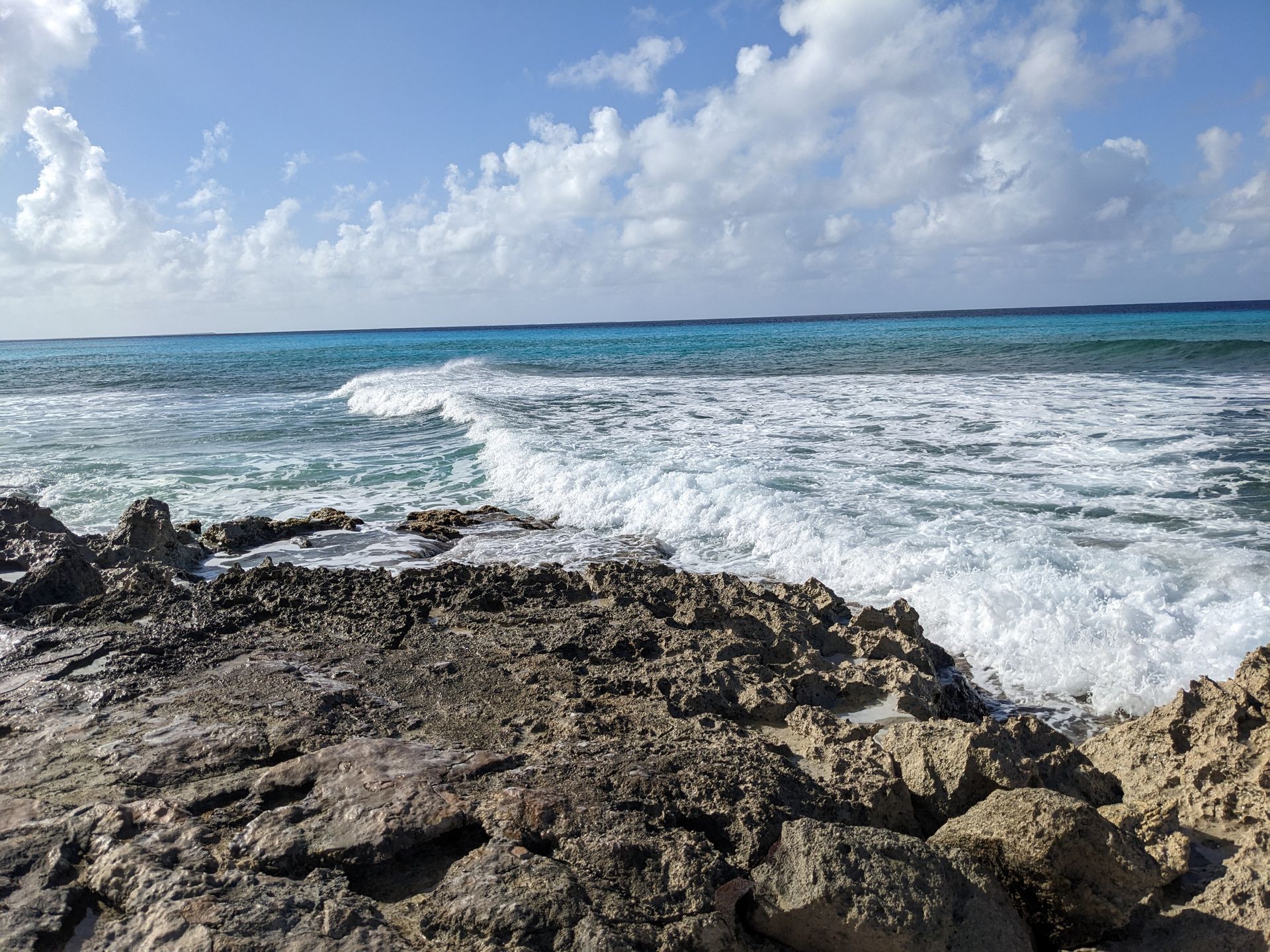 Waves crashing against a rocky shoreline on a sunny day