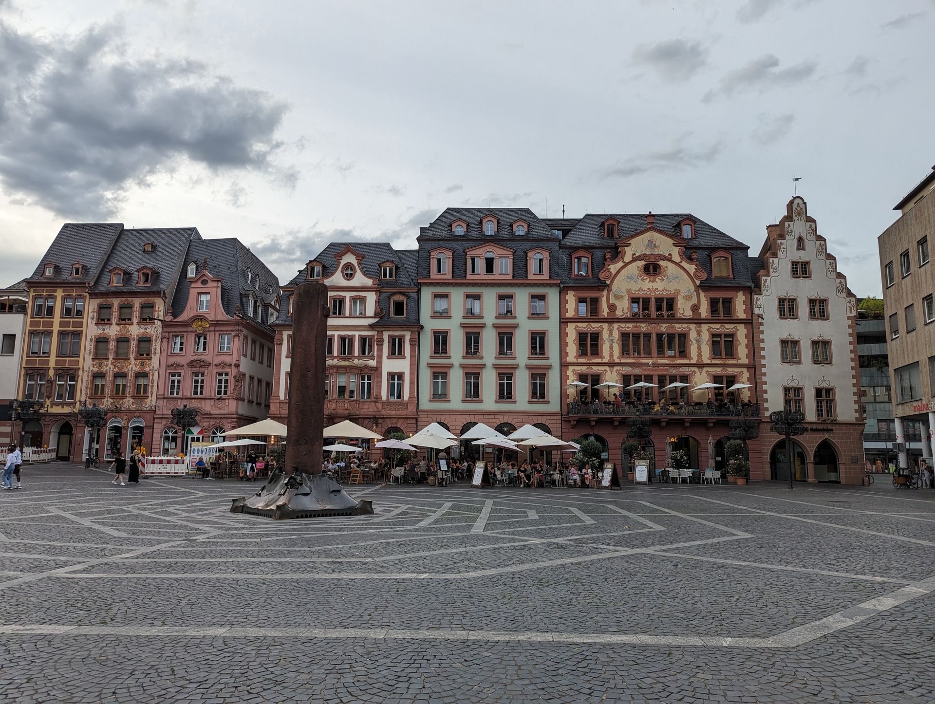 A row of buildings are lined up on a cobblestone square.