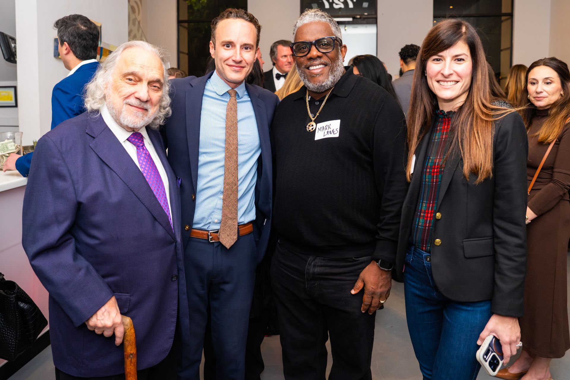 Four people in formal attire pose for a photo at an event.